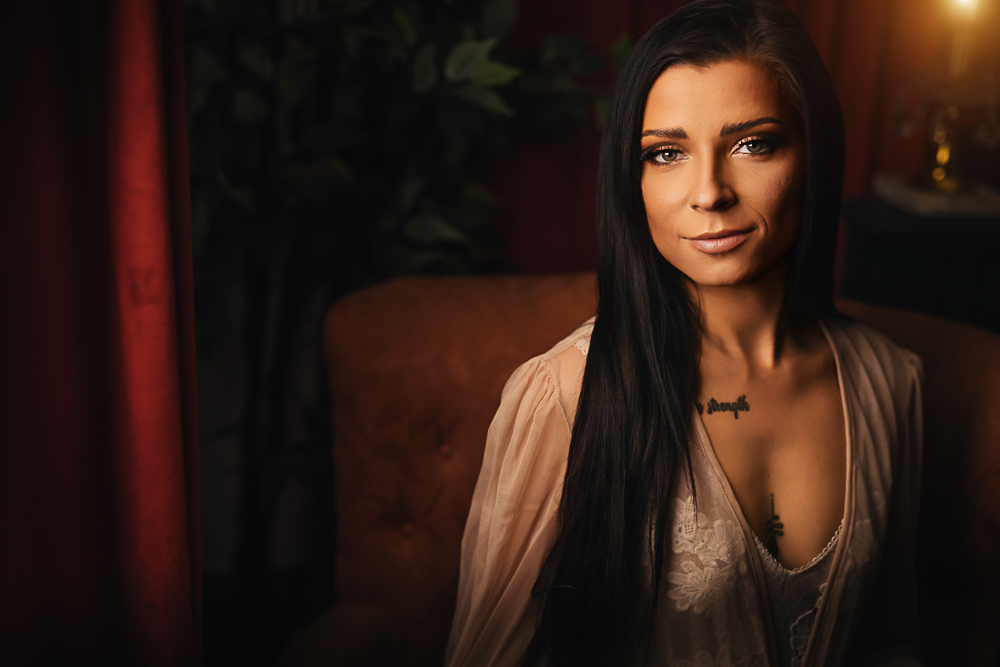Woman with long dark hair smiling in a sheer robe during a St. Louis boudoir session in the Lounge at Lafleur Boudoir.