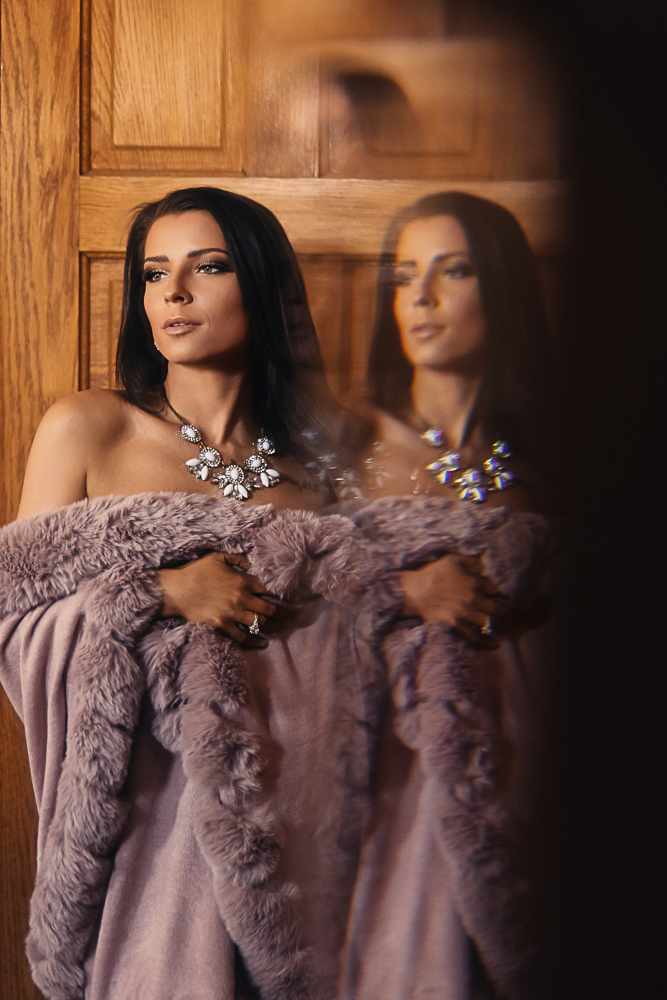 Elegant portrait of a woman wrapped in a faux fur shawl with an artistic reflection in the Grand Foyer.