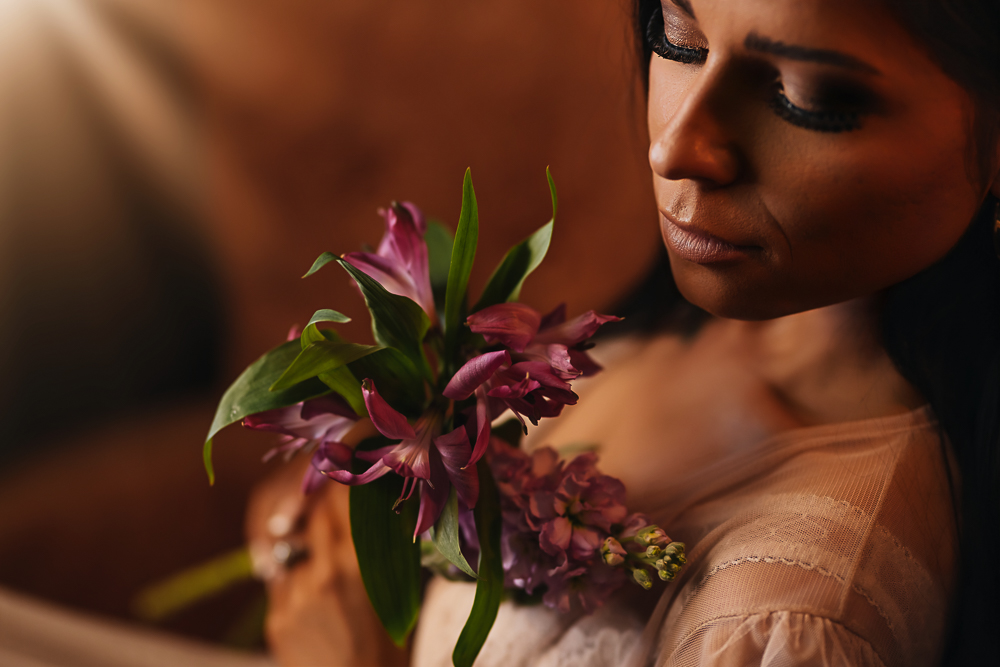 Close-up detail of a brunette woman holding fresh purple flowers during a St. Louis boudoir photography session.