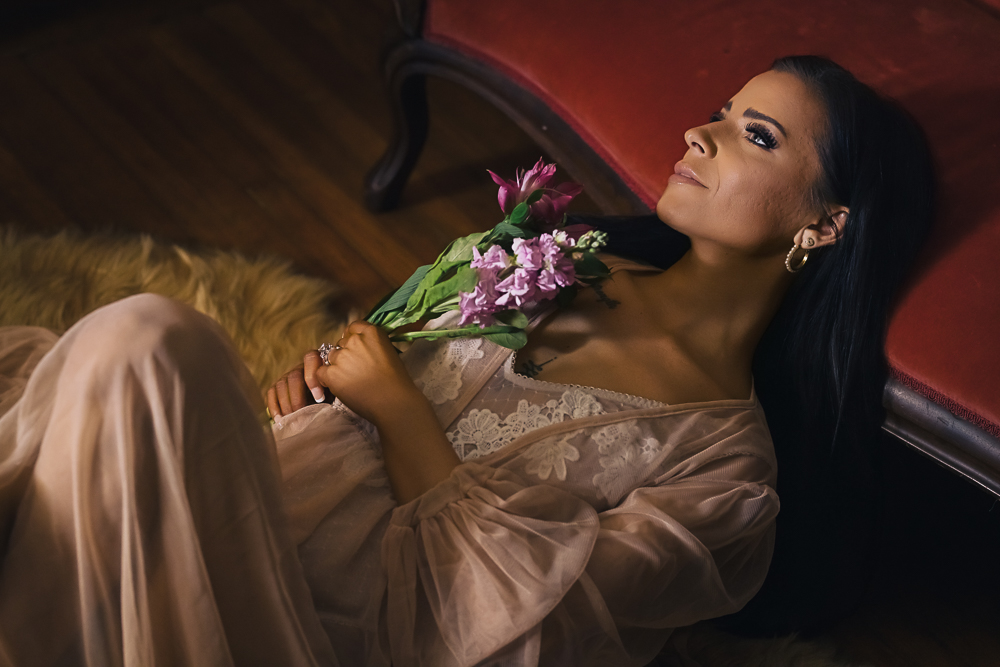 Woman reclining on a vintage sofa wearing a sheer robe during a luxury St. Louis boudoir session.
